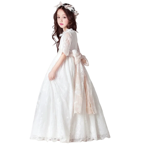 Young girl wearing a white lace dress with a pink sash on a white background