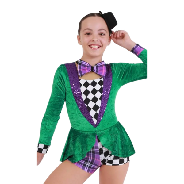 A young girl modeling a green and purple jester-themed costume with a black-and-white checkered vest front, matching plaid shorts, a purple bow tie, and a small black hat against a plain white background.
