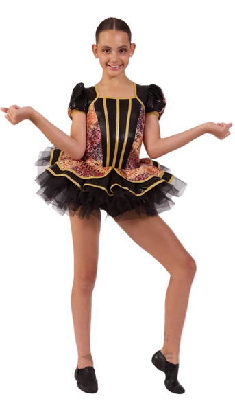 A young girl modeling a black and gold dance costume with a patterned bodice, puff sleeves, and a black tutu skirt, posed against a white studio background.