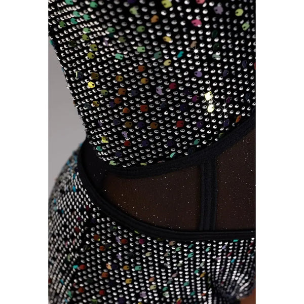 Close-up of a black embellished garment covered in silver rhinestones with scattered multicolored sequins, featuring sheer black mesh panels.