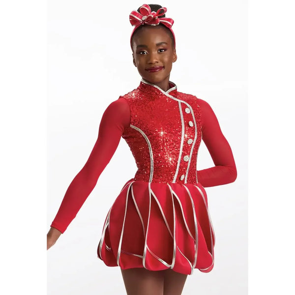 A young female dancer wearing a red long-sleeve dance/teddy costume with silver trim and a matching red headband with a bow, posed against a white studio background.