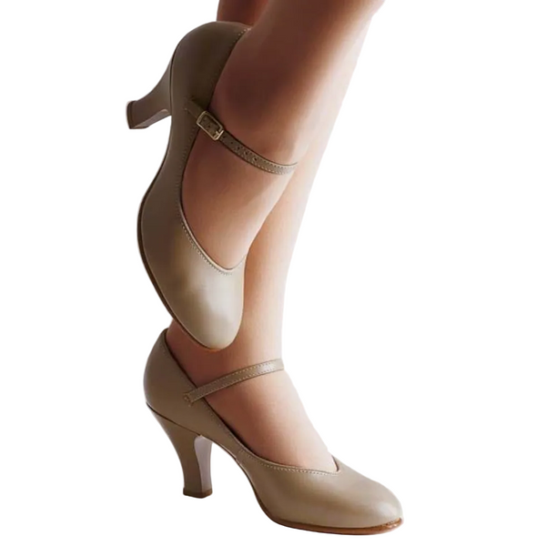 A pair of beige character shoes with a notch to heel design, padded insole, and a full Cambrelle sock lining, displayed on a model leg.